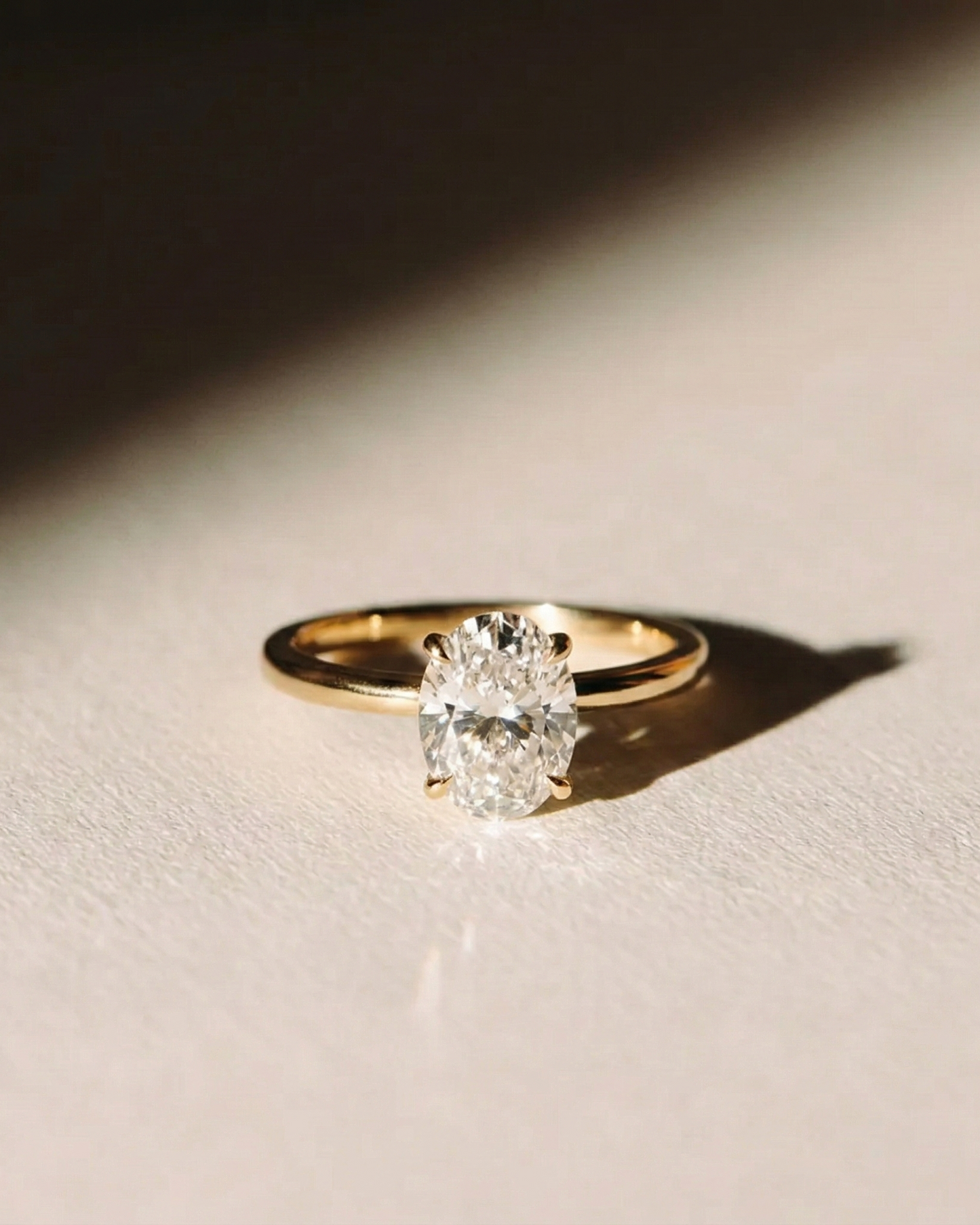 Oval Solitaire Diamond Ring on beige surface — yellow gold with large oval diamond — Stone Symphony