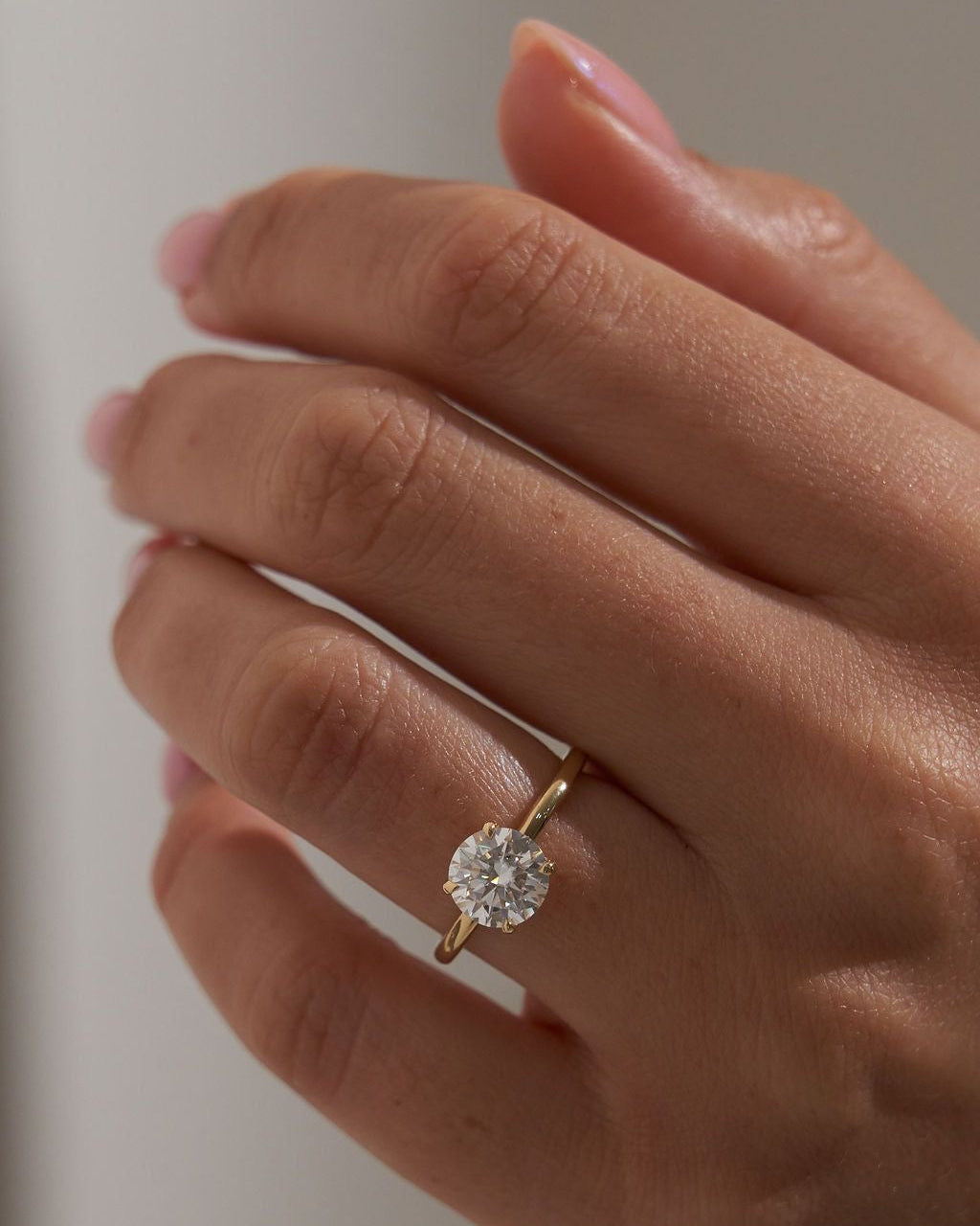 Brilliant Round Diamond Solitaire Ring on hand — sparkling round brilliant diamond in yellow gold — Stone Symphony