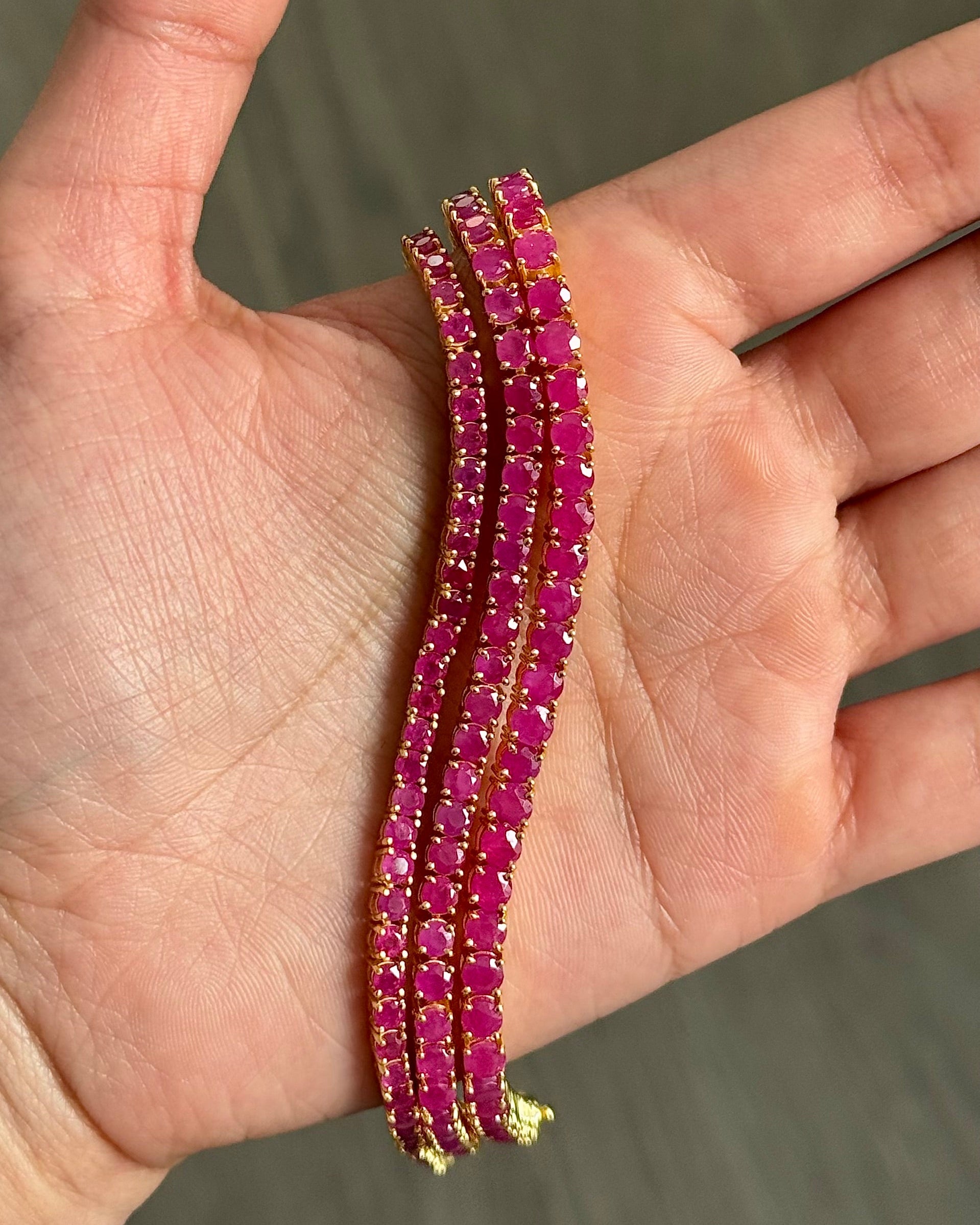 Classic Ruby Tennis Bracelet 18K gold vermeil — three ruby bracelets held in palm showing vivid deep red ruby stones — Stone Symphony