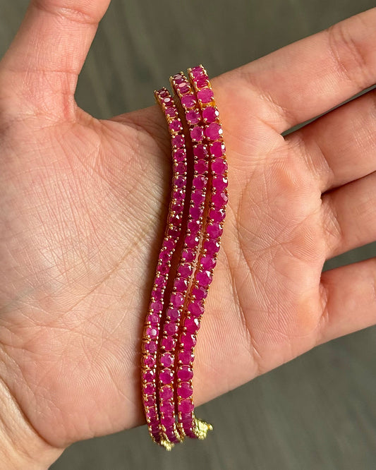 Classic Ruby Tennis Bracelet 18K gold vermeil — three ruby bracelets held in palm showing vivid deep red ruby stones — Stone Symphony
