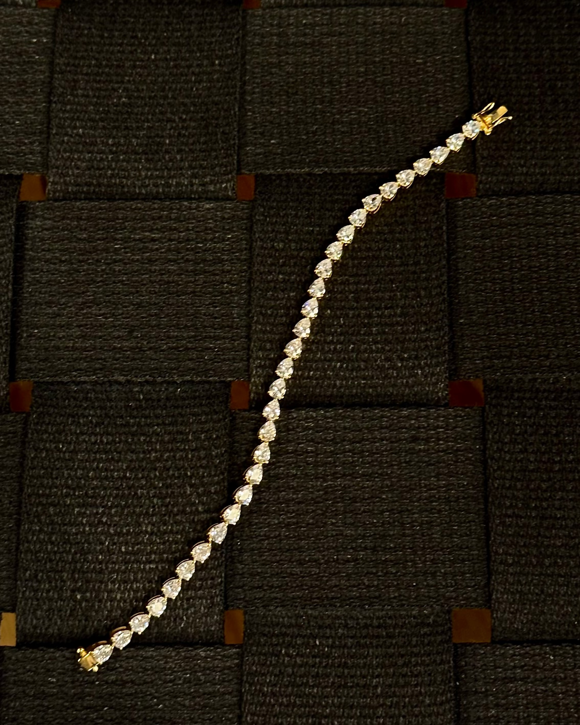 Dewdrop Pear Tennis Bracelet Gold Vermeil — pear-cut stones in gold vermeil, laid flat on woven dark surface — Stone Symphony