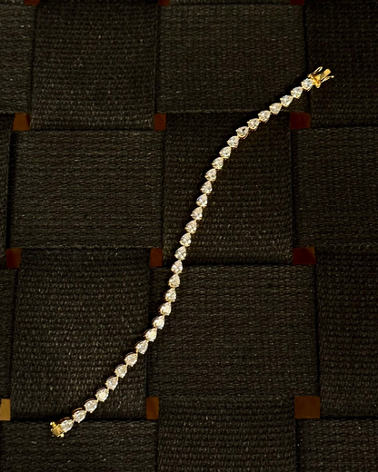 Dewdrop Pear Tennis Bracelet Gold Vermeil — pear-cut stones in gold vermeil, laid flat on woven dark surface — Stone Symphony