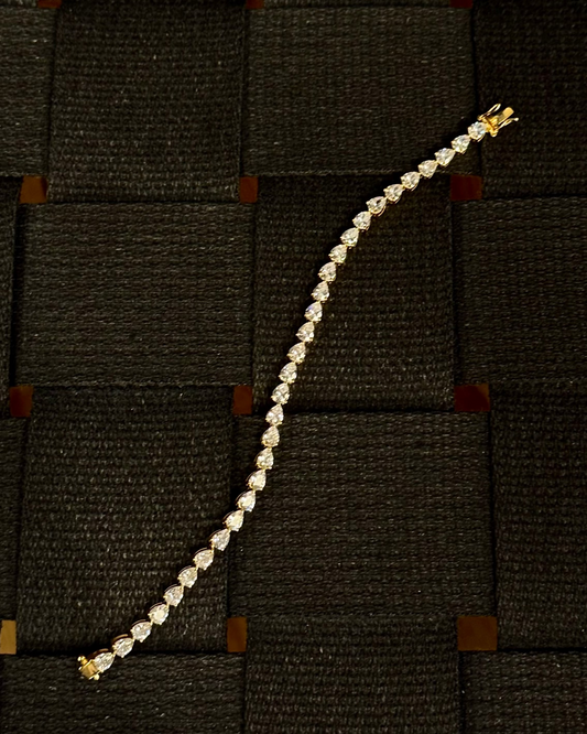 Dewdrop Pear Tennis Bracelet Gold Vermeil — pear-cut stones in gold vermeil, laid flat on woven dark surface — Stone Symphony